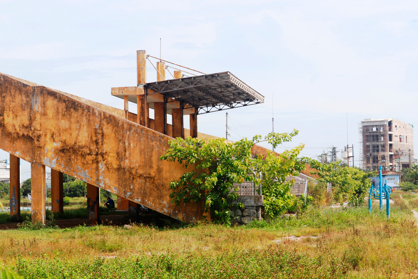 Các hạng mục nhà chức năng bị bỏ hoang, dụng cụ thể dục ngoài trời phủ đầy cỏ hoang, khán đài đầy rác thải và cây dại.