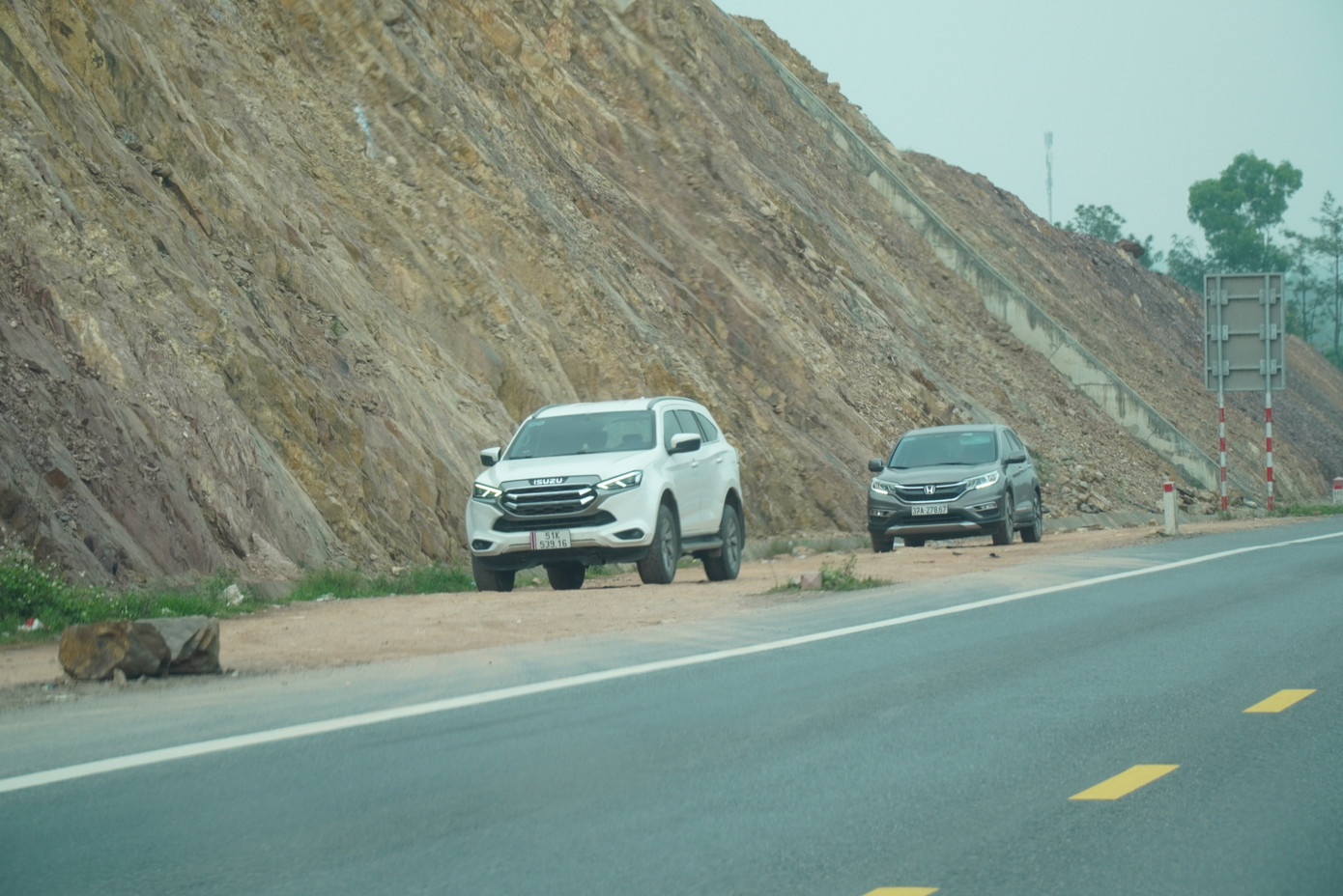 Xe ô tô phải dừng đỗ trên dải lề chưa hoàn thiện ven cao tốc, với nền đất và những vật cản.