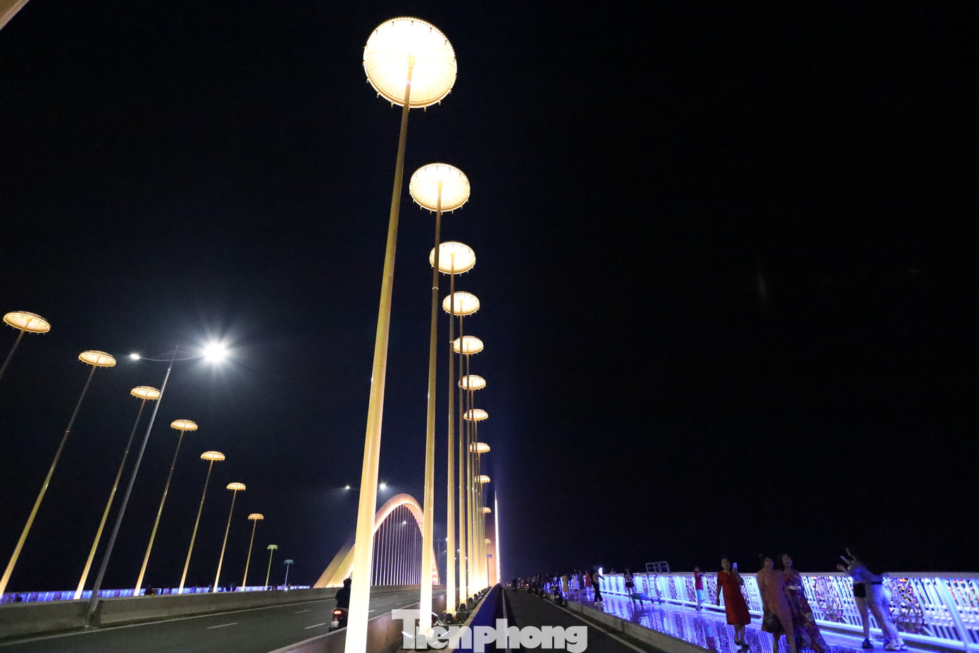 Hệ thống đèn LED công nghệ cao được thiết kế theo từng khu vực, cho phép chuyển đổi hàng trăm sắc màu khác nhau, tạo nên hiệu ứng thị giác ngoạn mục, phản chiếu lung linh trên mặt nước phẳng lặng như gương. Đặc biệt, 60 cột đèn nghệ thuật dọc theo cầu được lấy cảm hứng từ hình ảnh “lọng che vua” trong kiến trúc cung đình Huế. Ánh sáng từ các cột đèn như những chiếc vương miện lấp lánh, vừa trang trọng, vừa huyền ảo.