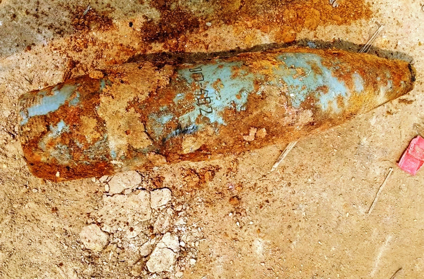 Vật bằng kim loại sơn màu xanh xám được xác định là đạn pháo chưa nổ còn sót lại sau chiến tranh. Ảnh: CTV Vật bằng kim loại sơn màu xanh xám được xác định là đạn pháo chưa nổ còn sót lại sau chiến tranh. Ảnh: CTV