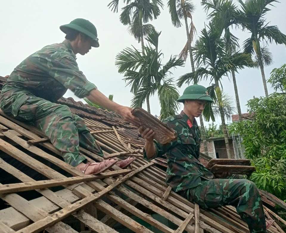 Bộ đội giúp dân lợp lại mái nhà bị tốc mái.