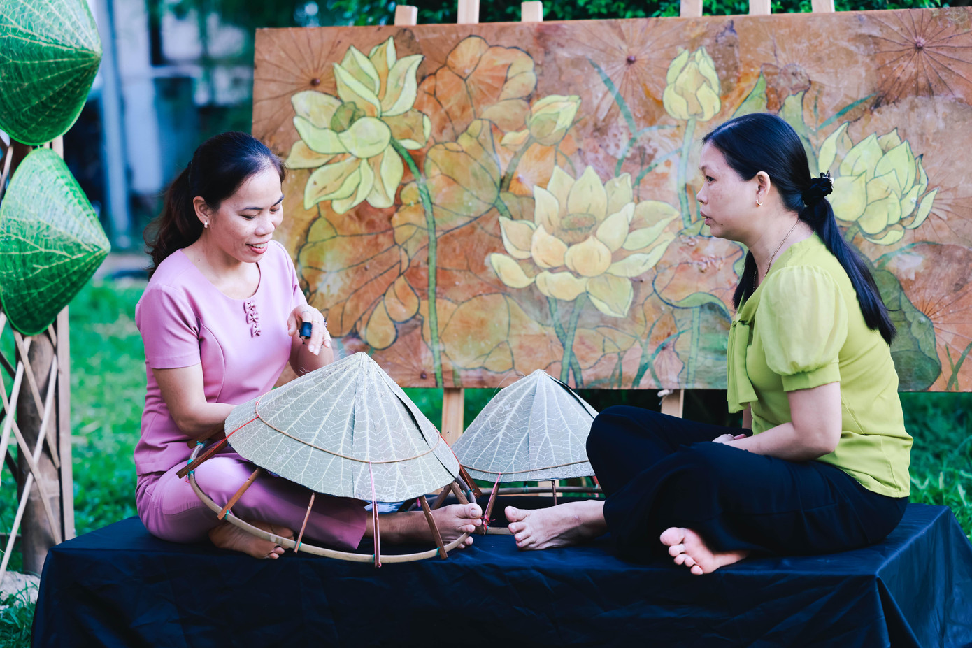 Trình diễn chế tác nón bằng chất liệu lá sen dưới bàn tay khéo léo của người phụ nữ Huế. Ảnh: Nguyễn Đình Chiến