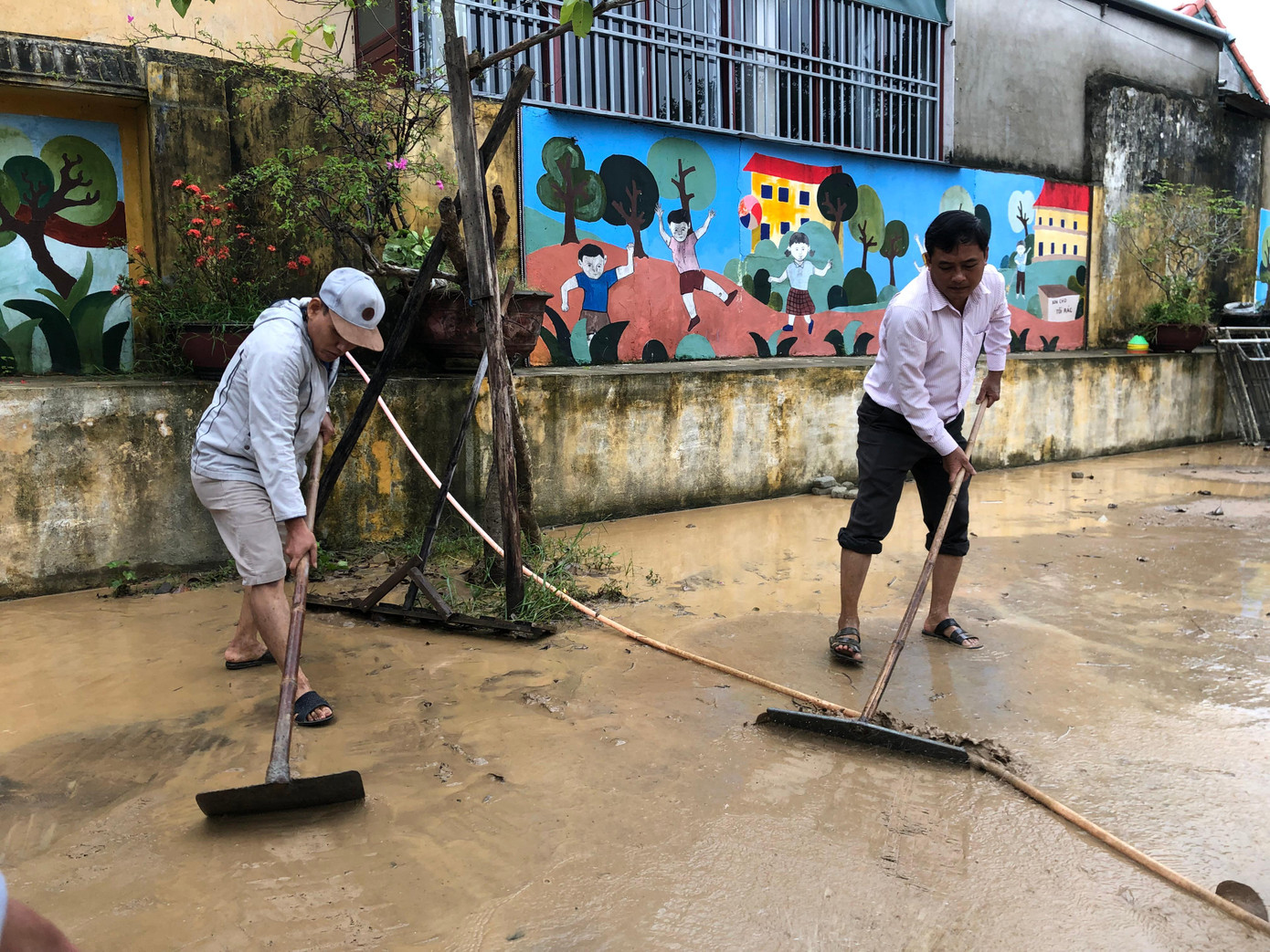 Giáo viên tại xã Quảng An gom dọn bùn đất, vệ sinh khuôn viên trường