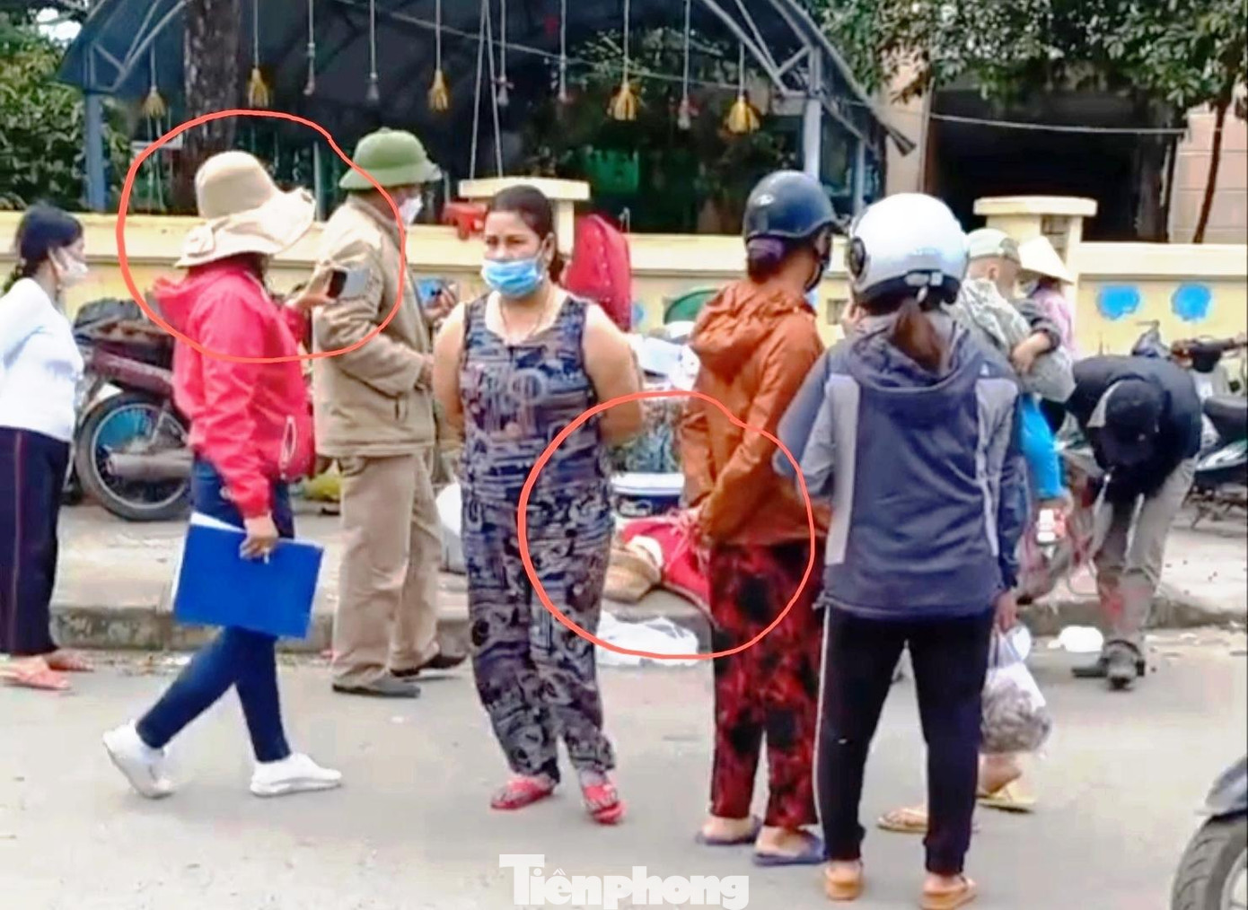 Trưởng ban quản lý chợ Tứ Hạ (đội mũ cối) đứng nhìn, nhân viên kế toán chợ (áo đỏ, tay cầm tập hồ sơ xanh) dùng điện thoại quay phim, cùng một nhân viên khác của chợ (ngoài cùng bên phải) đang xáo hàng của dân bán trên vỉa hè cách xa chợ để phân loại, kiểm đếm, cân đong... mặc cho nạn nhân (áo đỏ, trong vòng tròn phía dưới) nằm bất động, bất tỉnh nhân sự hàng chục phút giữa nền đất (ảnh cắt từ clip) Trưởng ban quản lý chợ Tứ Hạ (đội mũ cối) đứng nhìn, nhân viên kế toán chợ (áo đỏ, tay cầm tập hồ sơ xanh) dùng điện thoại quay phim, cùng một nhân viên khác của chợ (ngoài cùng bên phải) đang xáo hàng của dân bán trên vỉa hè cách xa chợ để phân loại, kiểm đếm, cân đong... mặc cho nạn nhân (áo đỏ, trong vòng tròn phía dưới) nằm bất động, bất tỉnh nhân sự hàng chục phút giữa nền đất (ảnh cắt từ clip)