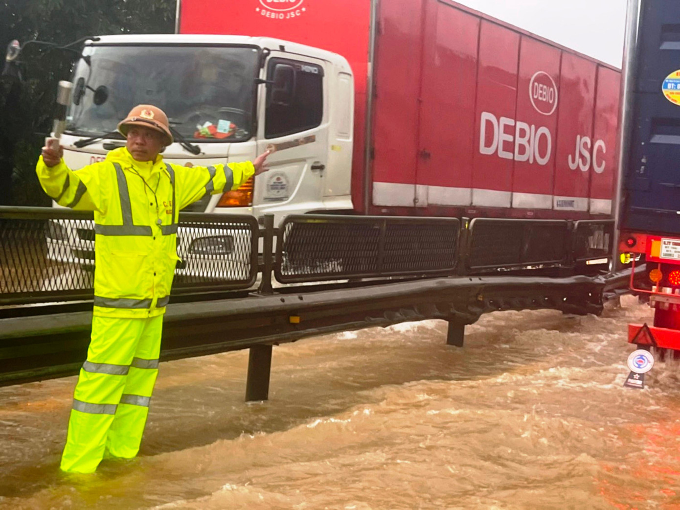 Hướng dẫn các phương tiện vận tải di chuyển an toàn qua đoạn đường ngập lụt. Ảnh: CA