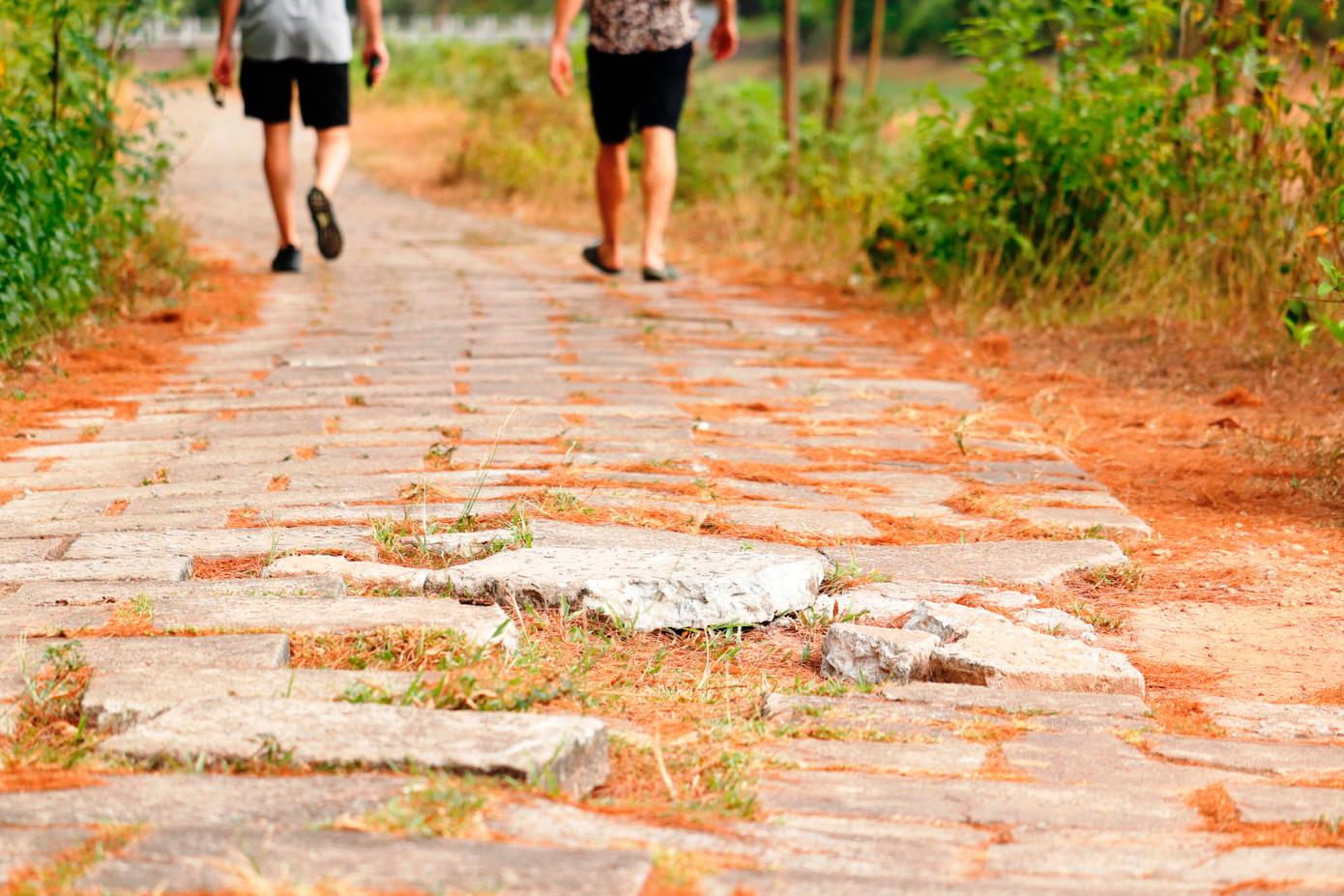 Hai du khách nước ngoài vượt qua một đoạn đường bị bong vỡ các tấm lát ven hồ. (Ảnh: Ngọc Văn)