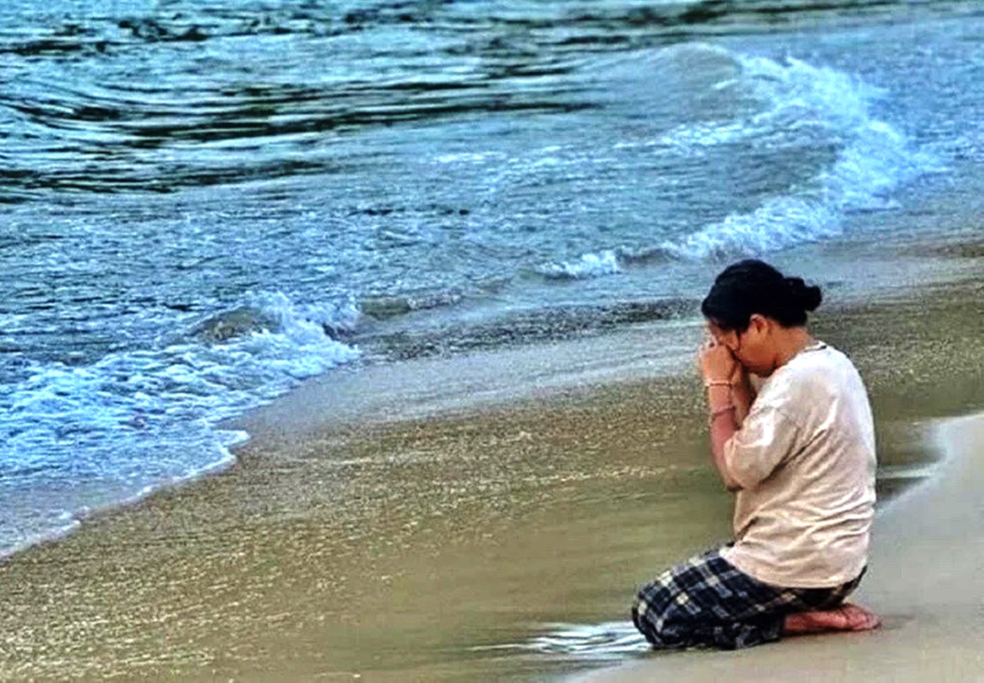 Hình ảnh mẹ cháu bé hàng ngày ra bờ biển quỳ ngóng con trai khiến nhiều người không cầm được nước mắt. Ảnh: MXH