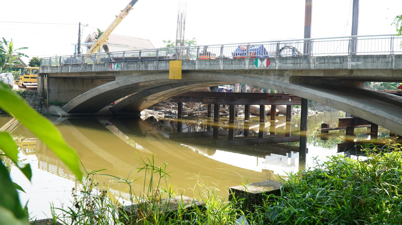 Sau khi hoàn thành thi công các hạng mục cơ bản của cây cầu vào cuối năm 2018 đầu năm 2019, do thiếu hai đường dẫn đấu nối với hai đầu cầu từ phía đường Hải Triều và Tôn Quang Phiệt, nên công trình giao thông trị giá 32 tỷ này nằm “lọt thỏm” và mắc kẹt giữa lòng sông Lợi Nông, không thể thông xe đưa vào sử dụng