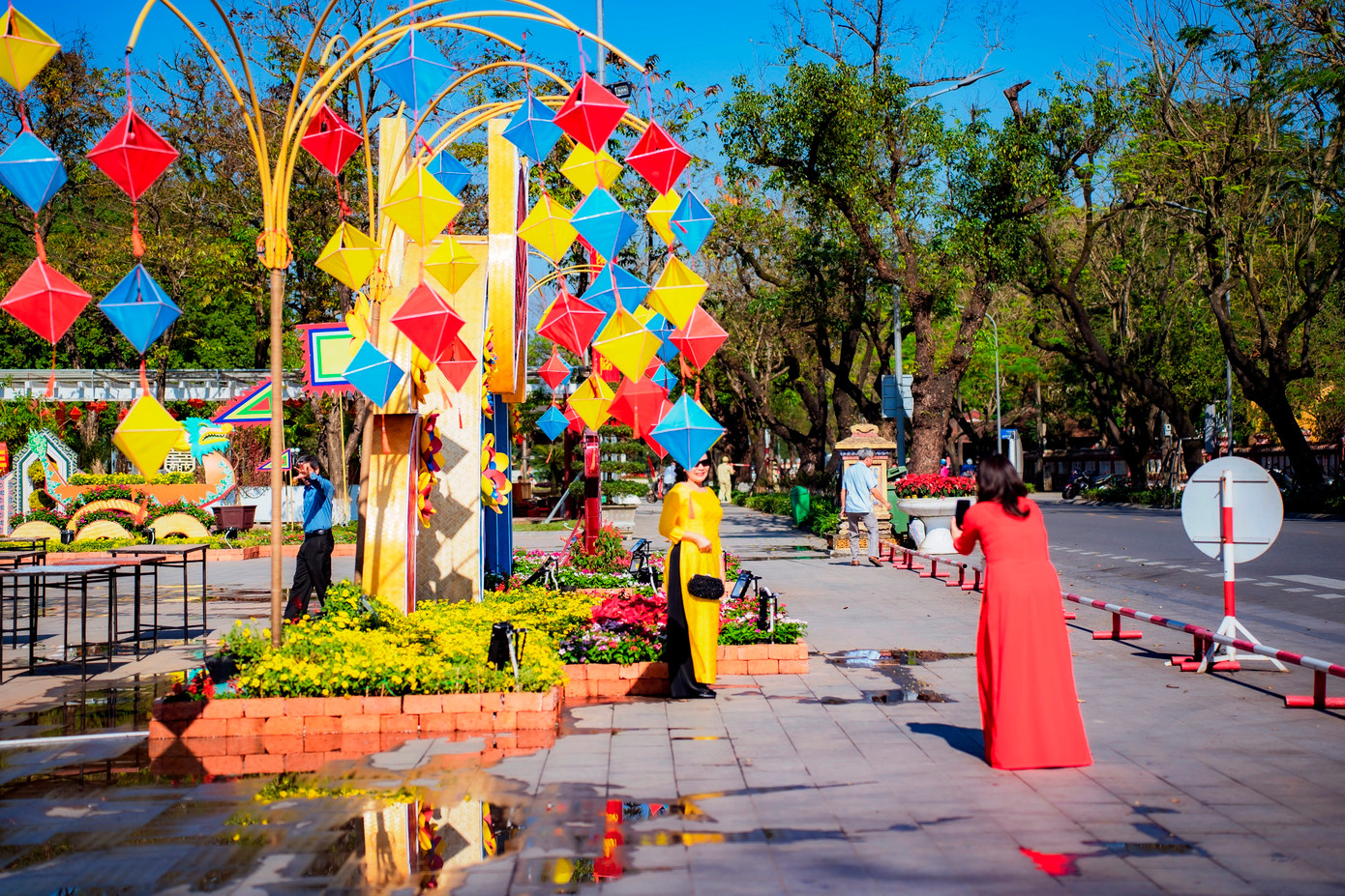 Du khách vận áo dài truyền thống thích thú chụp hình lưu niệm bên cụm trang trí bằng đèn lồng truyền thống và hoa lá ngày xuân cạnh trường Quốc học Huế. Ảnh: Đình Hoàng