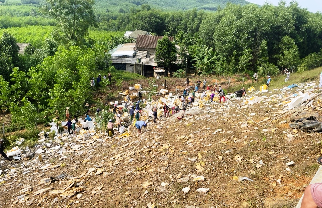 Người dân hỗ trợ chủ xe, tài xế thu gom hàng bị rơi vãi ra cả một góc vực bên đường cao tốc. (Ảnh: H.P)