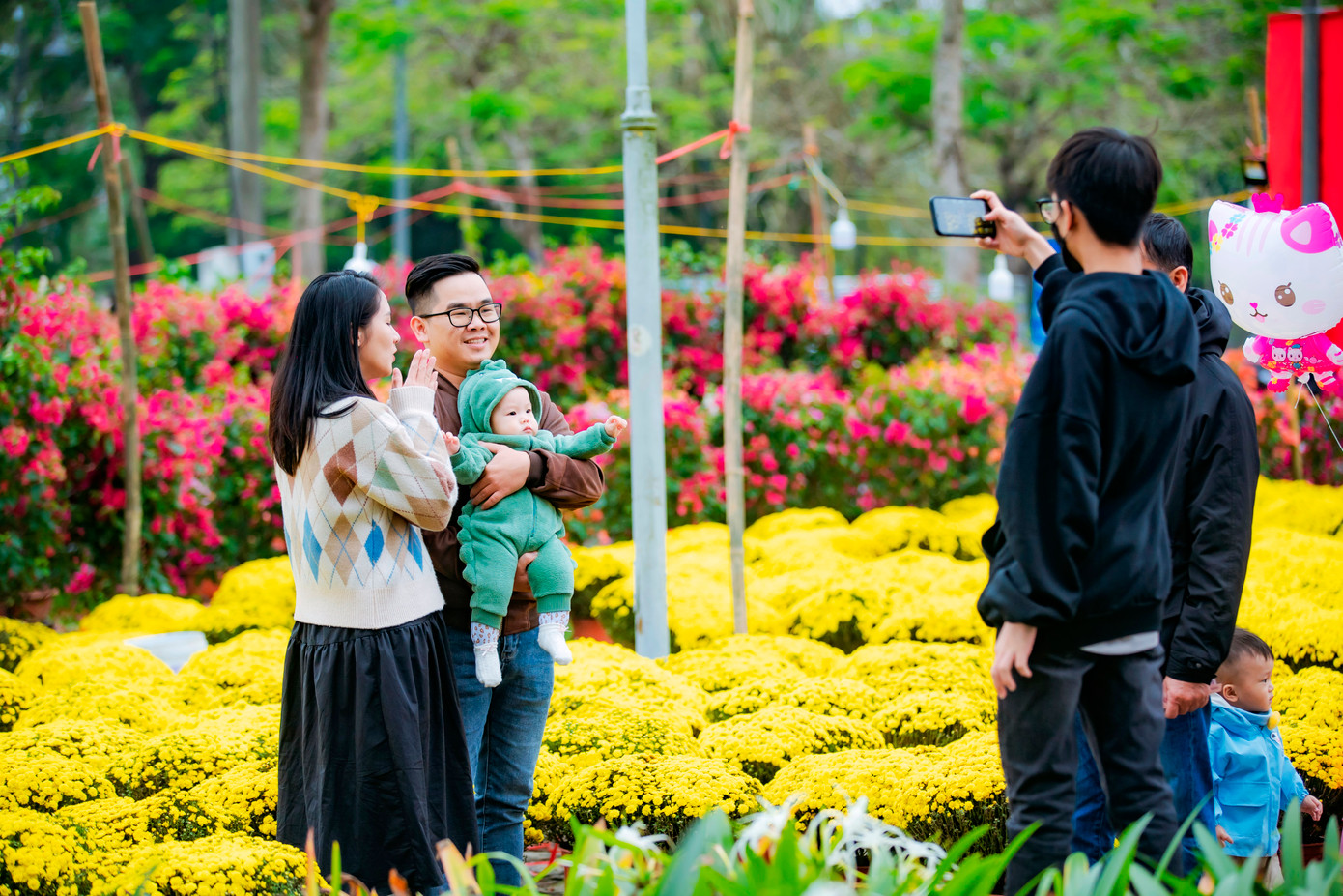 Đôi vợ chồng trẻ cùng con nhỏ chụp hình lưu niệm bên hoa Tết xứ Huế. Ảnh: Đình Hoàng