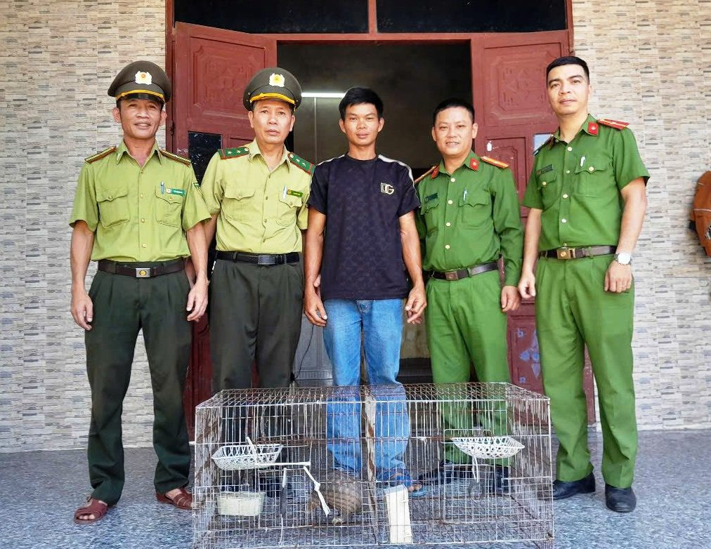 Ông Lê Công Thành (áo phông đen) giao nộp cá thể tê tê quý hiếm cho kiểm lâm.