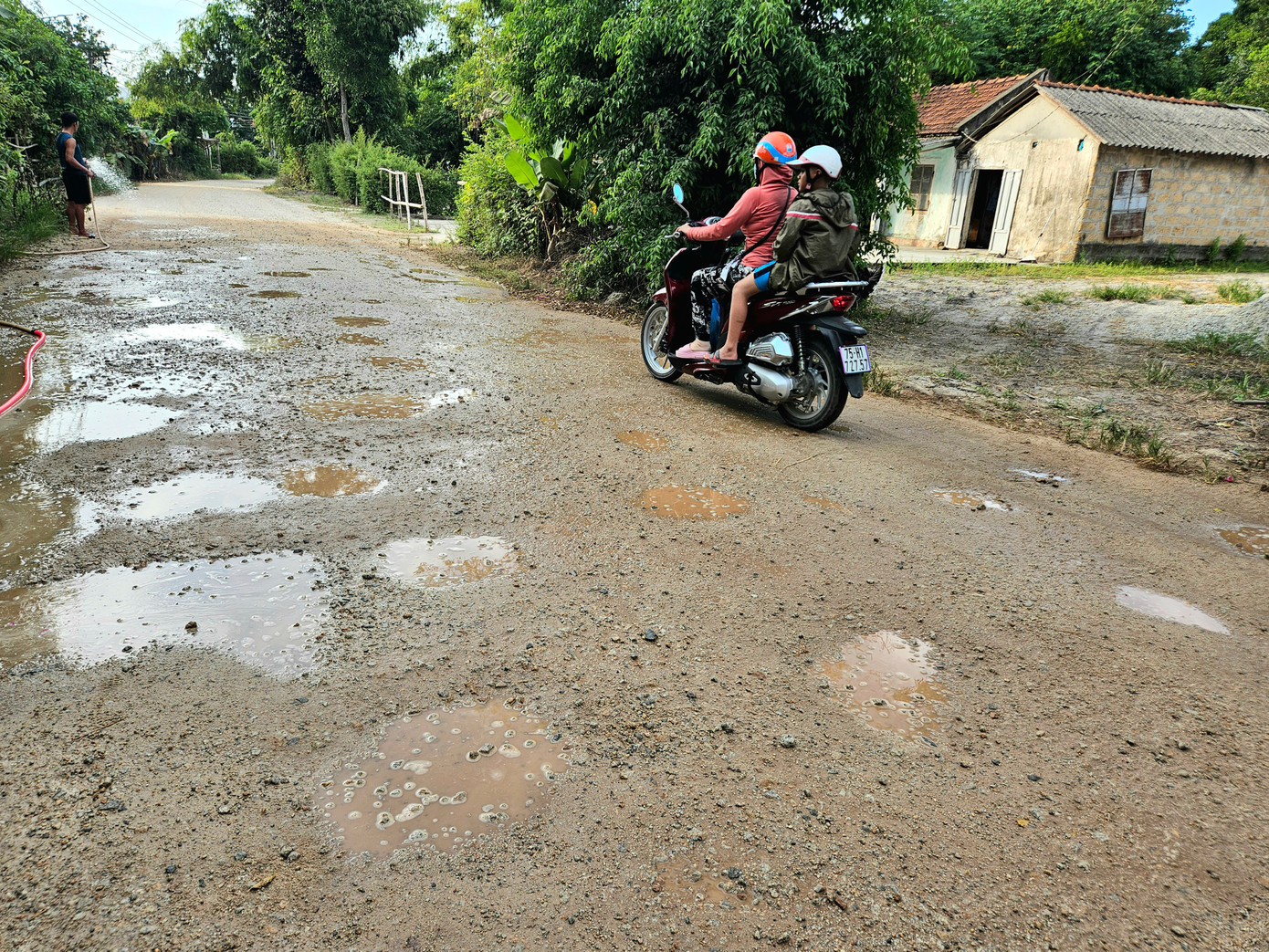 Gần nơi ở của bà Tầm là nhà anh Phan Văn Khánh (44 tuổi). Gia đình anh Khánh hàng ngày phải dùng vòi nước để xịt bụi thường xuyên bốc lên và xộc vào nhà từ con đường đã xuống cấp nghiêm trọng.
