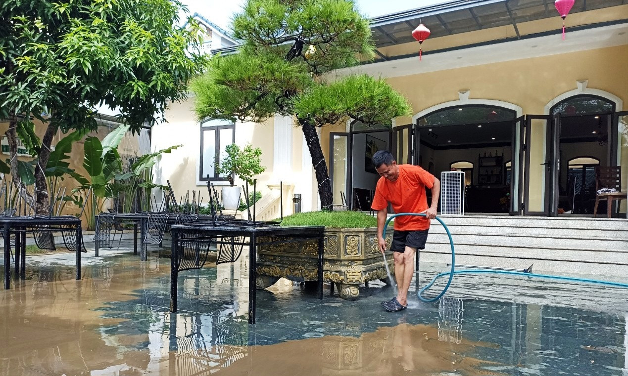 Đẩy rửa bùn đất ra khỏi hàng quán sau nhiều ngày bị ngâm trong lụt.