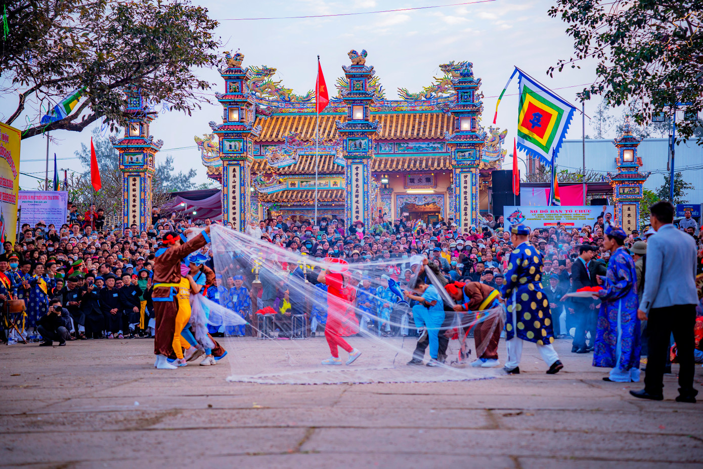 Lúc “đàn cá” lượm tiền, các chủ thuyền khiêng một chiếc ghe tiến vào sân đình. Những người ngồi trên ghe tung lưới vây quanh đám trẻ. Trò diễn "bủa lưới" là trò trình nghề mang đậm tính chất lễ nghi. Ảnh: Đình Hoàng