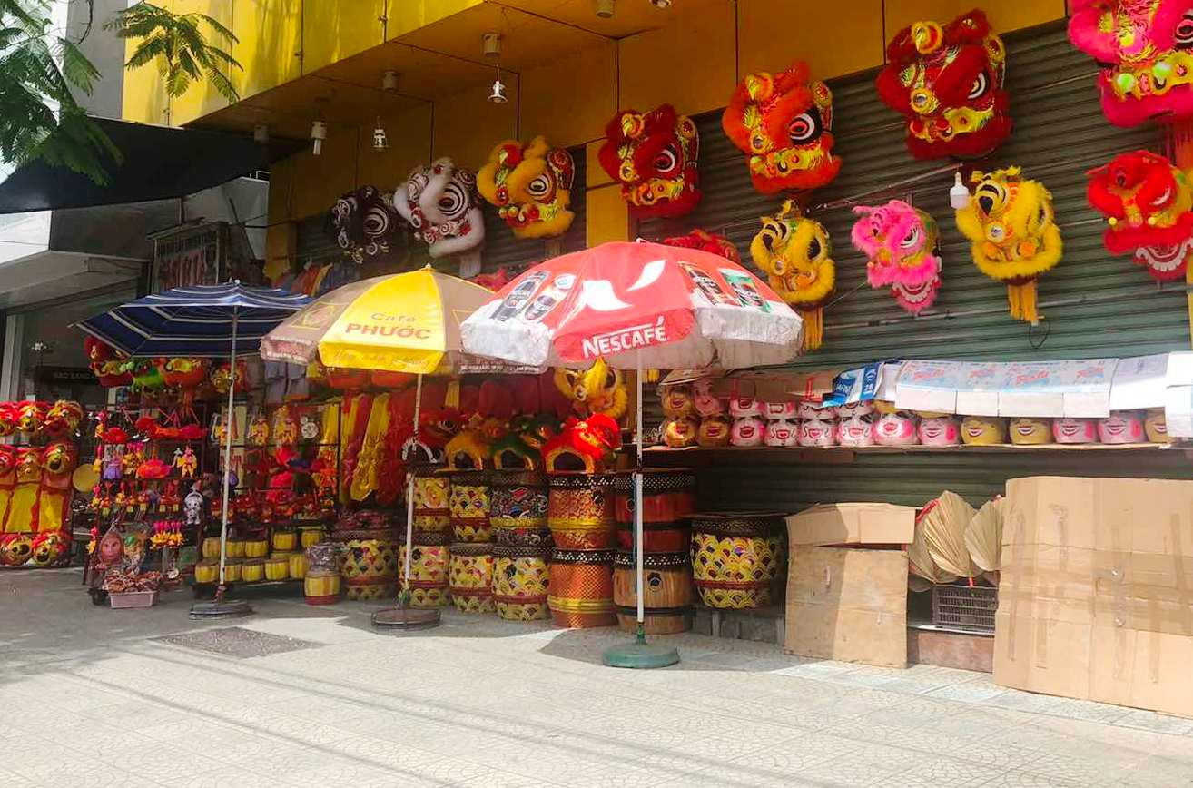 Anh N.R (ngụ TP Huế), một nghệ nhân làm nghề đầu lân Huế, chia sẻ: “Do dịch bệnh nên nhu cầu mua bộ đầu lân về chơi của người dân giảm sút nặng nề. Các năm trước, cứ vào cuối tháng 7 âm lịch, cơ sở sản xuất của gia đình tui đã tiêu thụ hàng chục bộ đầu lân mỗi ngày. Vậy mà năm nay, số đầu lân bán ra chỉ dao động 1-2 bộ một ngày. Quá ế ẩm! Dịch bệnh khiến hàng sản xuất ra tồn đọng quá nhiều. Huế lại mưa ẩm thường xuyên, nên việc bảo quản hàng sang vụ lân sang năm không hề dễ", anh N.R than. Ảnh: Đìu hiu quầy bán đầu lân tại một con phố ở TP Huế