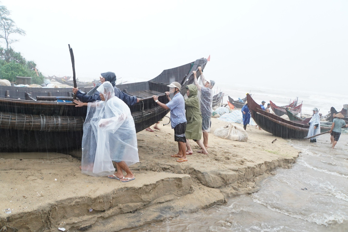 Lực lượng chức năng hỗ trợ ngư dân đưa ghe thuyền, ngư cụ ở khu vực sạt lở ven biển đến nơi an toàn.