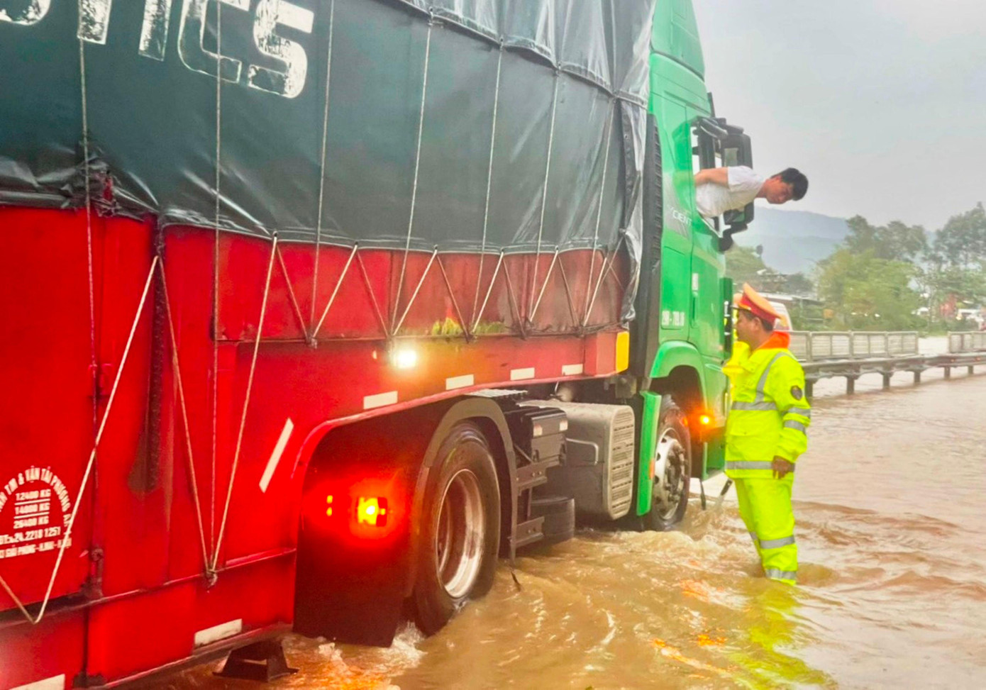 Hướng dẫn, hỗ trợ xe tải vượt qua đoạn đường ngập lụt nguy hiểm. Ảnh: CA