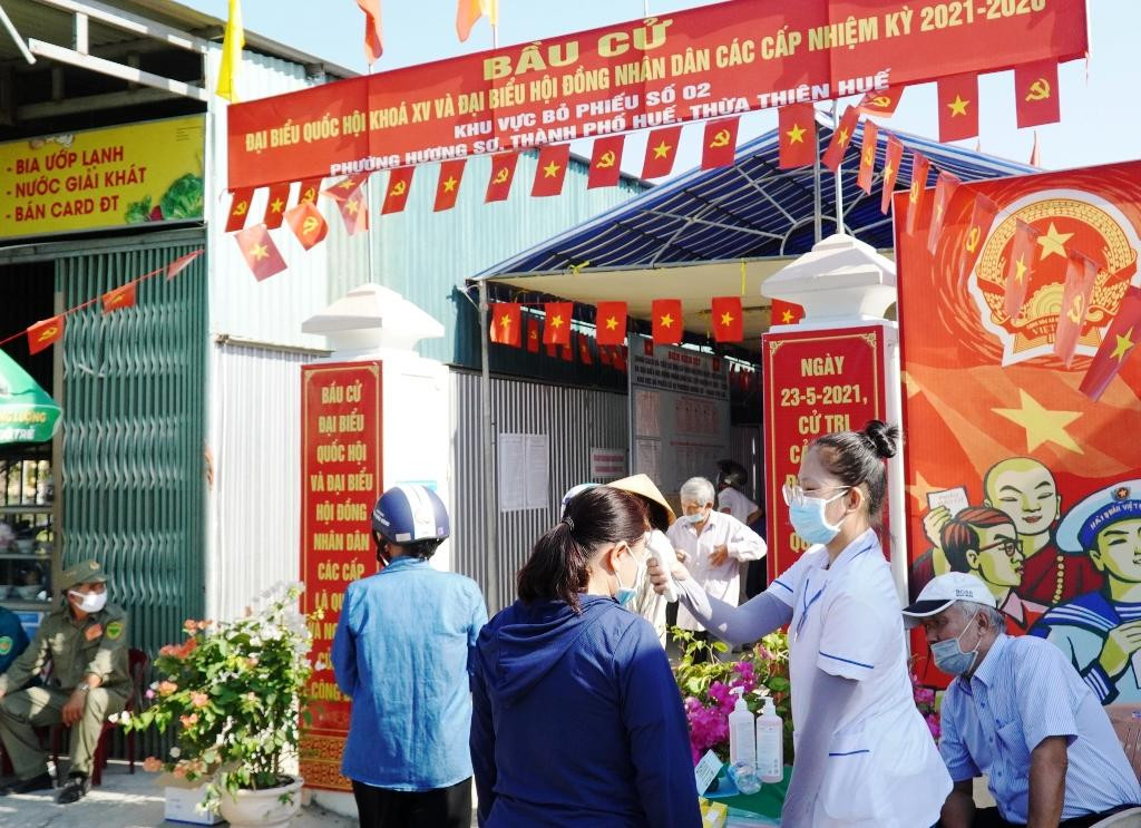 Túc trực để đo thân nhiệt, hướng dẫn sắp xếp cho cử tri vào làm thủ tục bỏ phiếu đúng quy định.