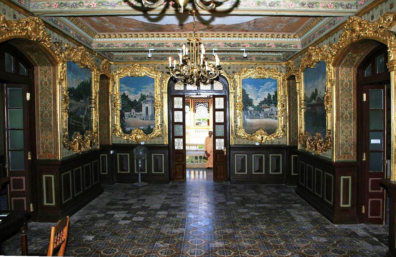 Nội thất đại sảnh của cung điện gồm 20 phòng. Trong đó, khu phòng khách và hai phòng chiêu đãi ở tầng 1 là nơi đáng lưu ý. Đặc biệt, trong phòng khách có sáu bức tranh tường hết sức nổi tiếng vẽ cảnh lăng các vua Gia Long, Minh Mạng, Thiệu Trị, Tự Ðức, Khải Ðịnh, Ðồng Khánh. Tranh vẽ bằng bột màu trên nền tường và những bộ khung thếp vàng bao quanh, 26 vòm cửa của cả căn phòng làm bằng gỗ mạ vàng với những hoa văn chạm trổ rất tinh vi, sinh động. Ảnh TL