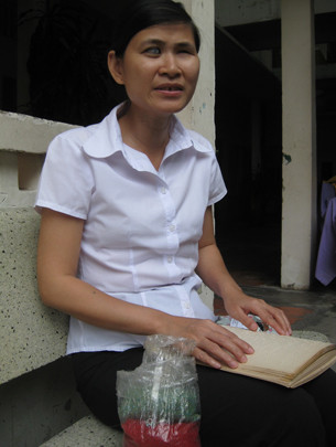 Sinh viên Nguyễn Thị Mến học bài môn tiếng Anh trên sách chữ nổi cô tự chép. Bên cạnh là bịch hạt cườm Mến mang theo để tranh thủ xâu móc chìa khóa vào giờ rảnh. Ảnh: M.Lâm