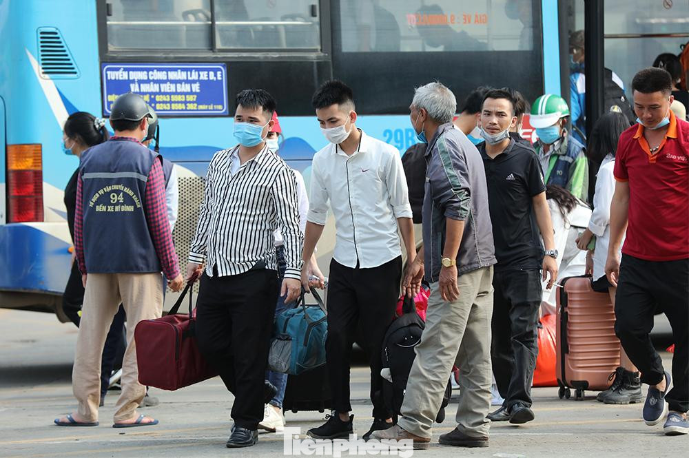 Bên ngoài điểm chờ xe buýt có khá đông người xách hành lý di chuyển vào bến xe