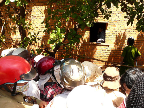 Người dân hiếu kì tụ tập quanh nhà nạn nhân