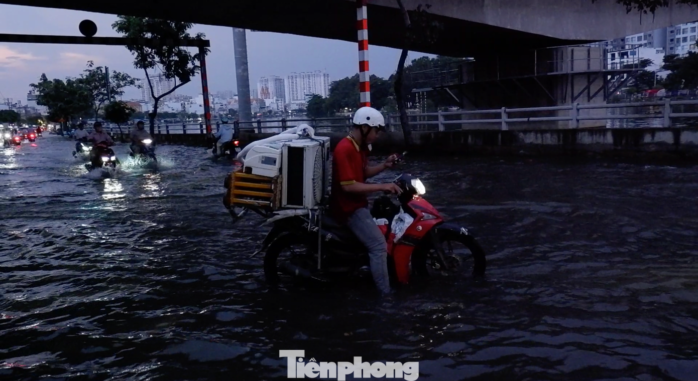 Xe bị &quot;chết máy&quot;, một nhân viên cửa hàng điện máy phải loay hoay giữa dòng nước.