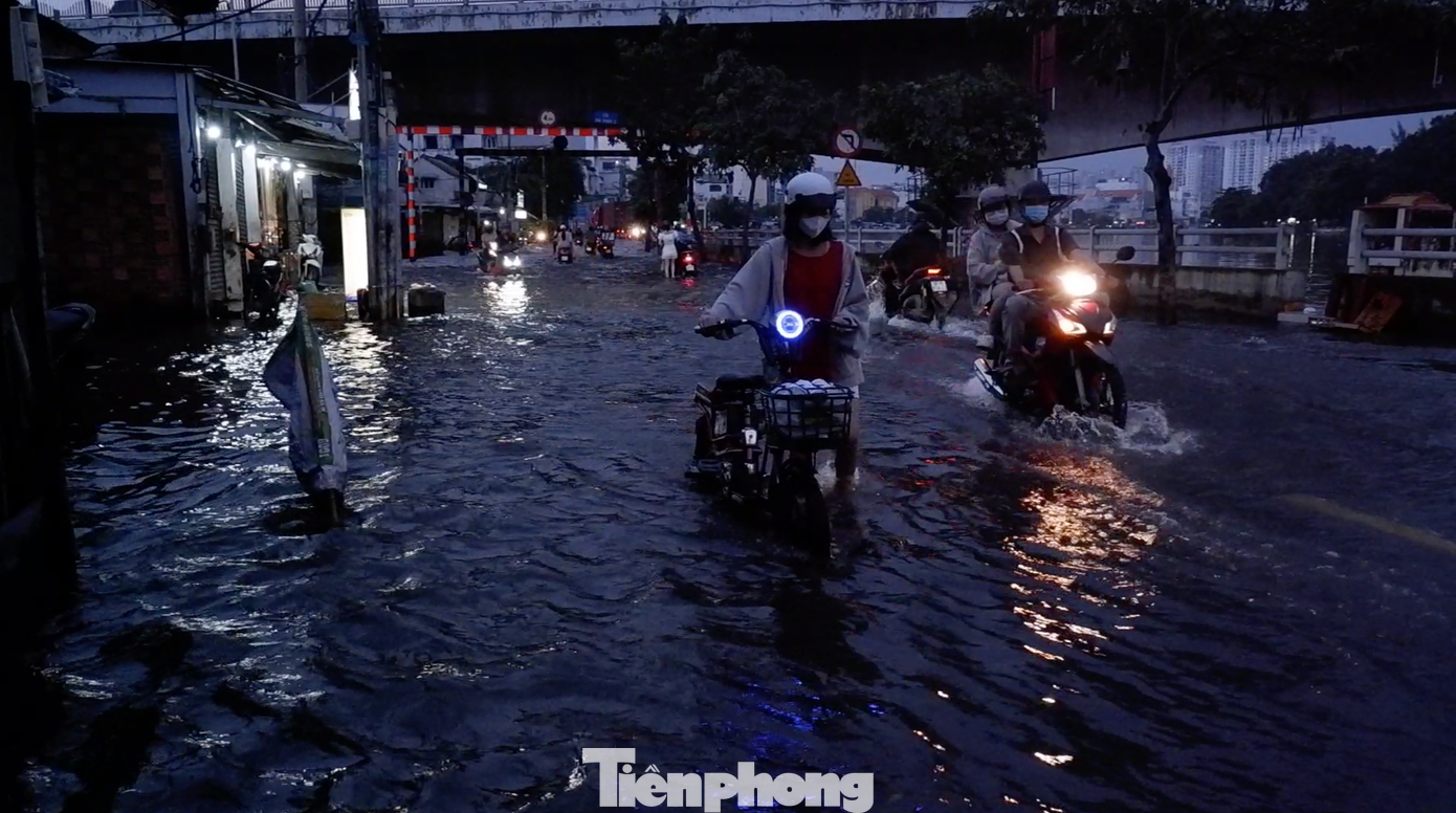 Người dân bì bõm lội nước dắt xe bị chết máy trên đường Trần Xuân Soạn.