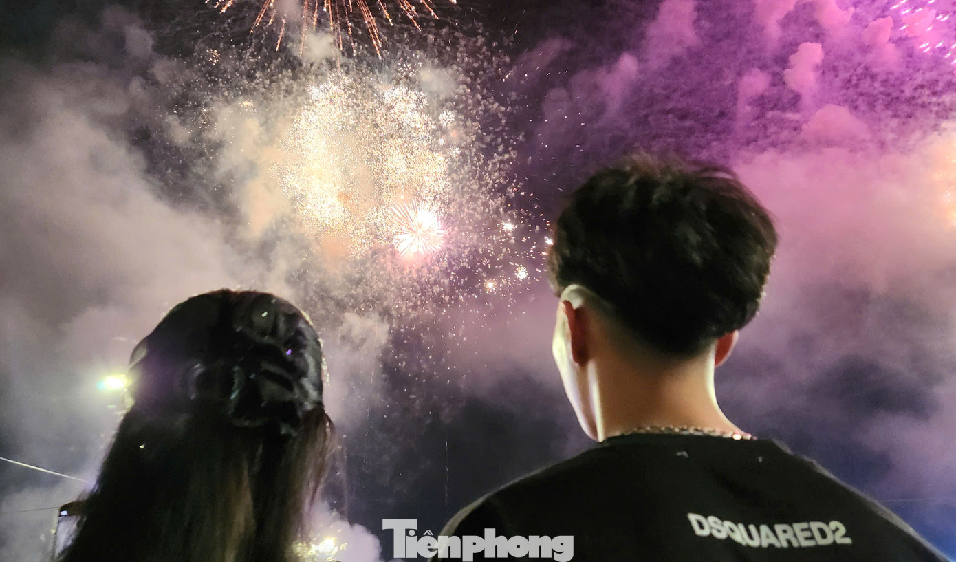 Nhiều cặp đôi tranh thủ ngắm pháo hoa hoặc dùng điện thoại ghi lại khoảnh khắc bên nhau dưới màn pháo hoa rực rỡ.