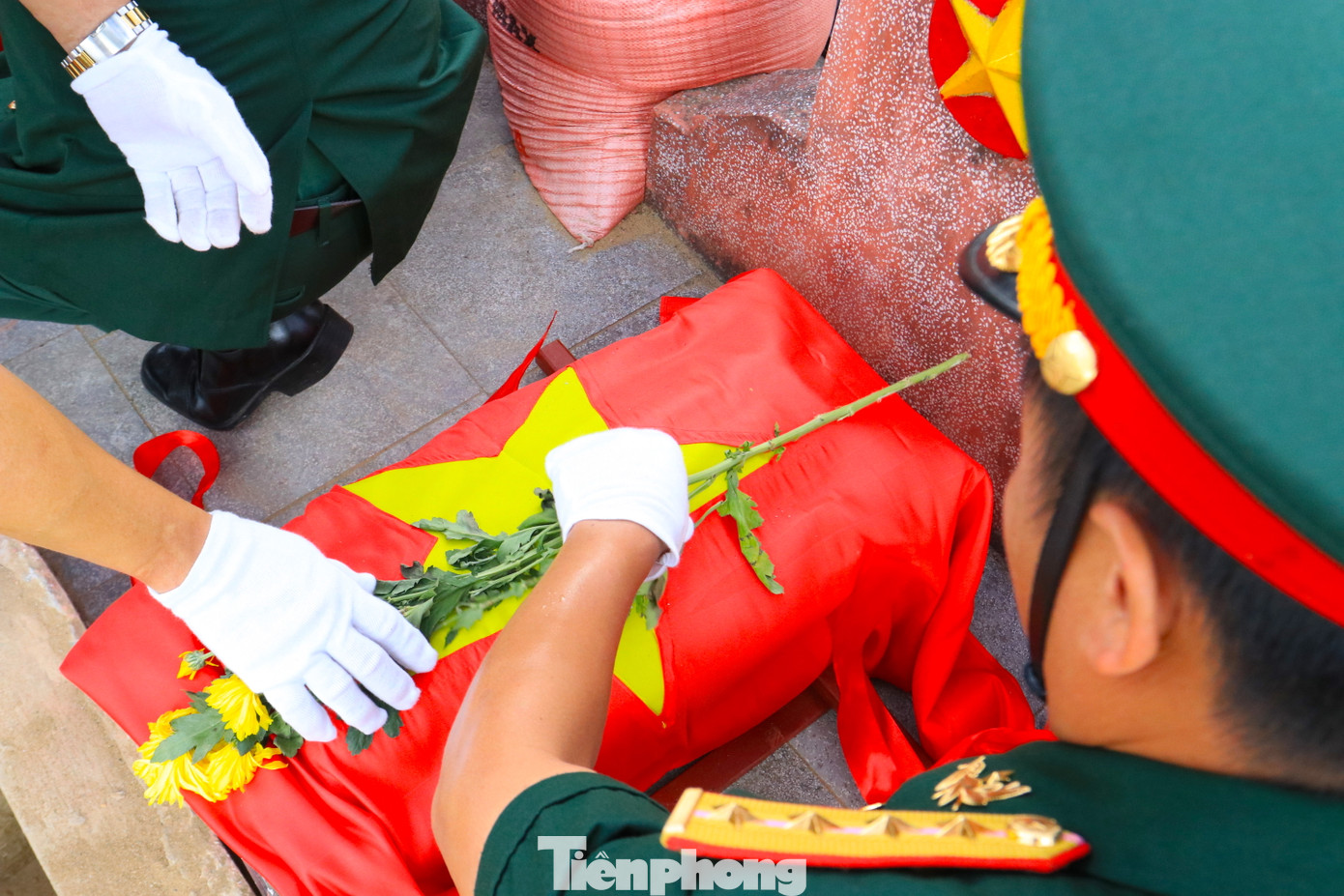 Hài cốt các anh hùng liệt sỹ được phủ lên lá cờ Tổ quốc tươi thắm và những bông hoa tươi đẹp.