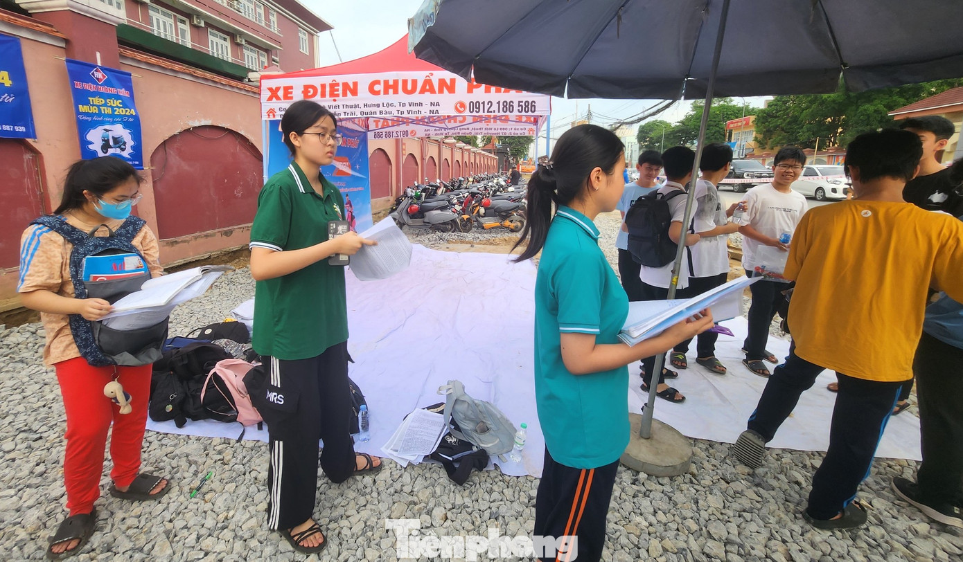 Nhiều em học sinh tranh thủ ôn tập ngay tại điểm gửi cặp ở cổng trường điểm thi.