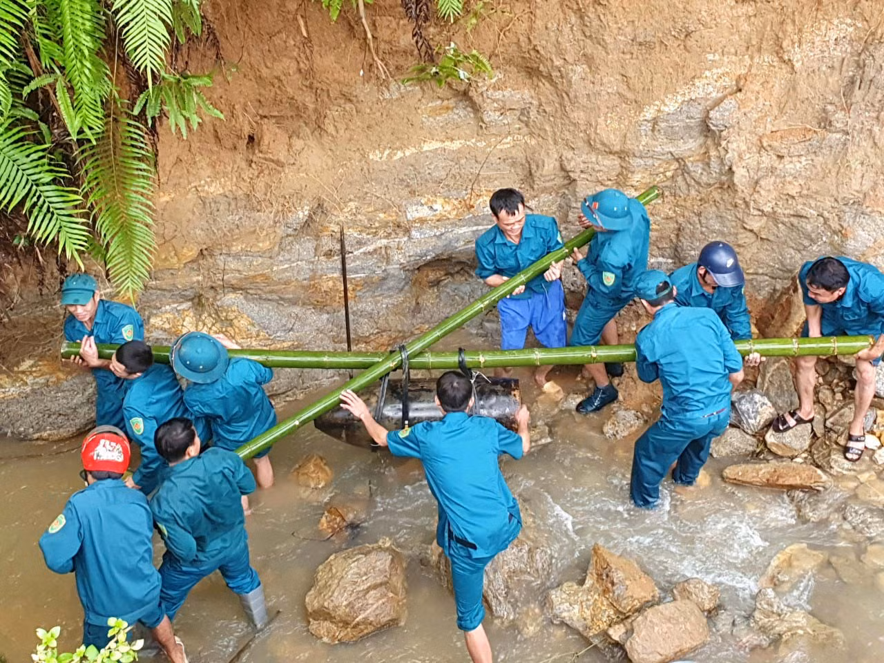 Dùng cây tre gánh vận chuyển quả bom đi tiêu hủy.