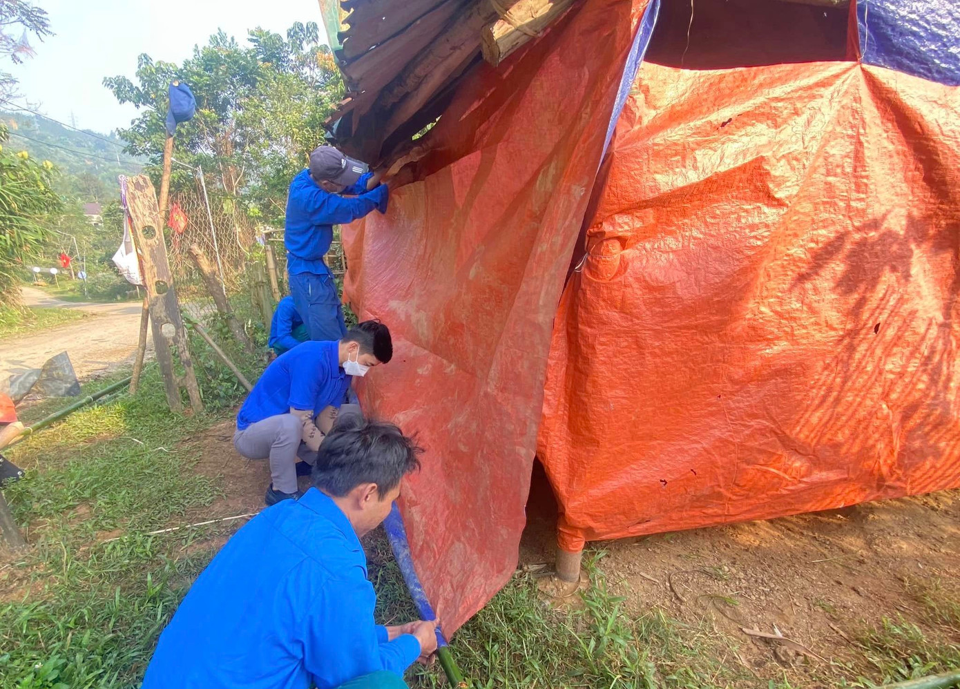 Các đoàn viên xã Mường Nọc (Quế Phong) hỗ trợ người dân may bạt, che chắn chuồng trại gia súc tránh rét.