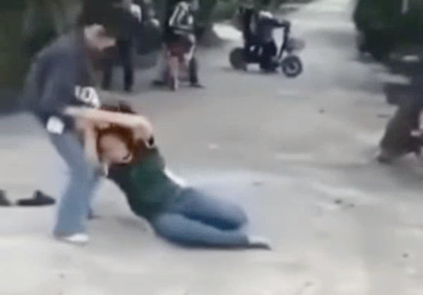 Khi một nữ sinh ngã, người còn lại tiếp tục túm tóc, dùng chân đạp mạnh vào người đối phương.