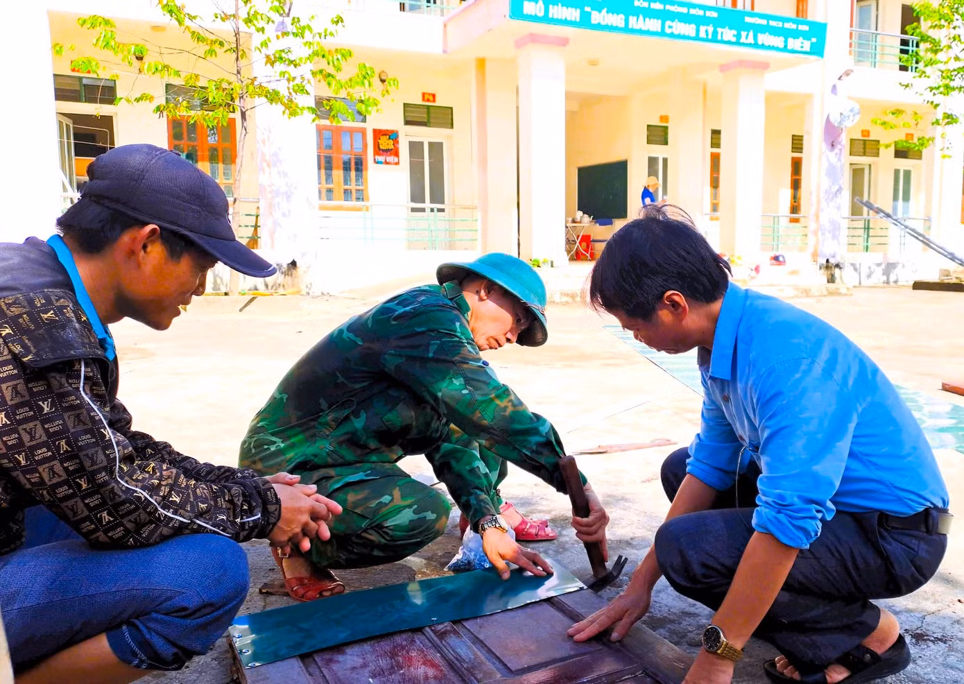 Các cán bộ chiến sĩ biên phòng cùng đoàn viên thanh niên sửa sang lại những cánh cửa đã bị mối mọt hư hỏng.