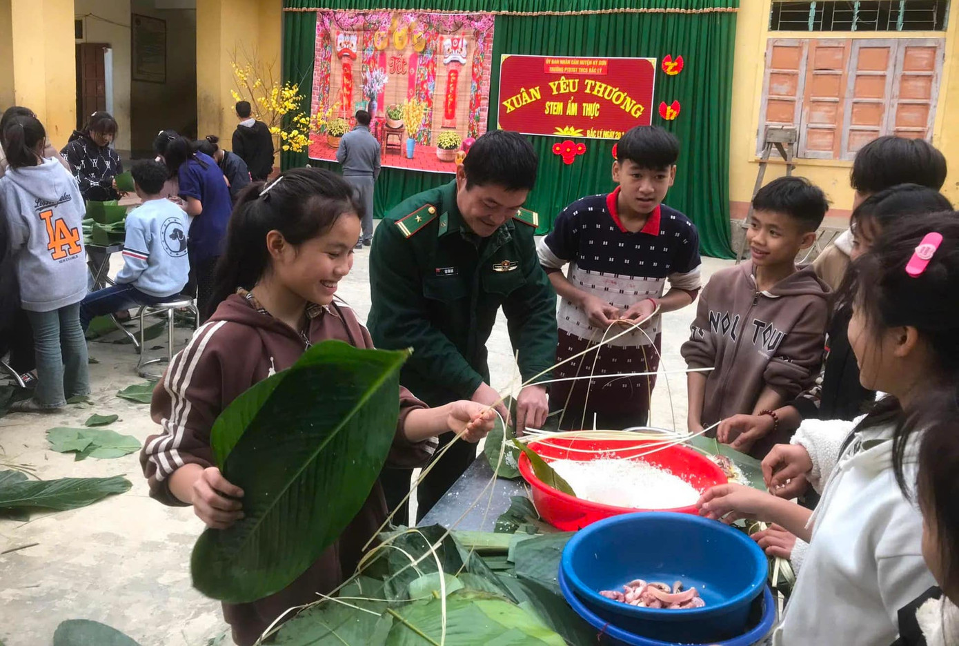 Các em học sinh thích thú khi được các chú bộ đội hướng dẫn gói bánh chưng cổ truyền.