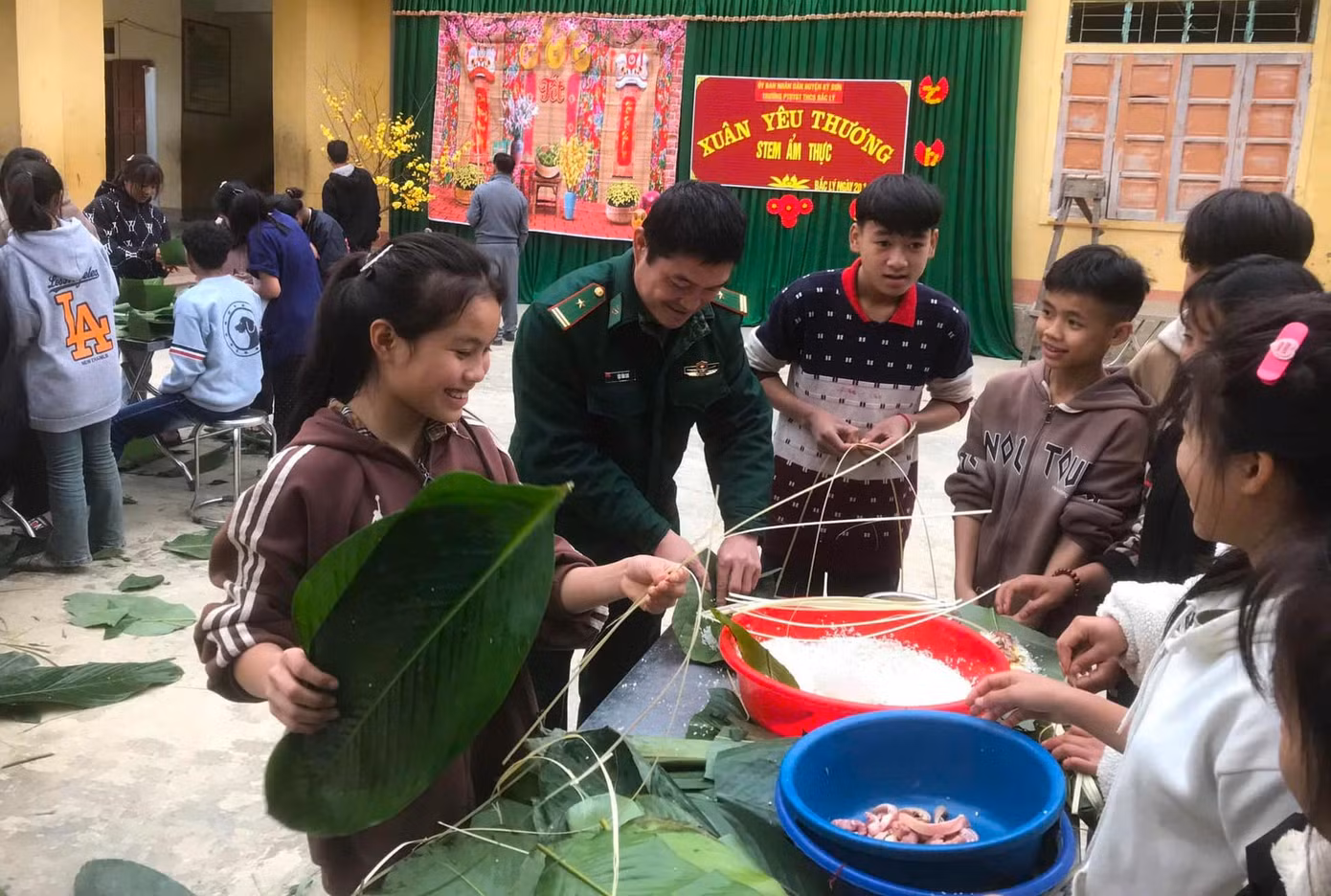 Các em học sinh thích thú khi được các chú bộ đội hướng dẫn gói bánh chưng cổ truyền.