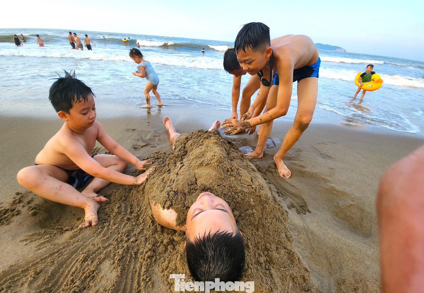 Nhiều em nhỏ dùng cát để đắp lên người rồi sảng khoái cười đùa.