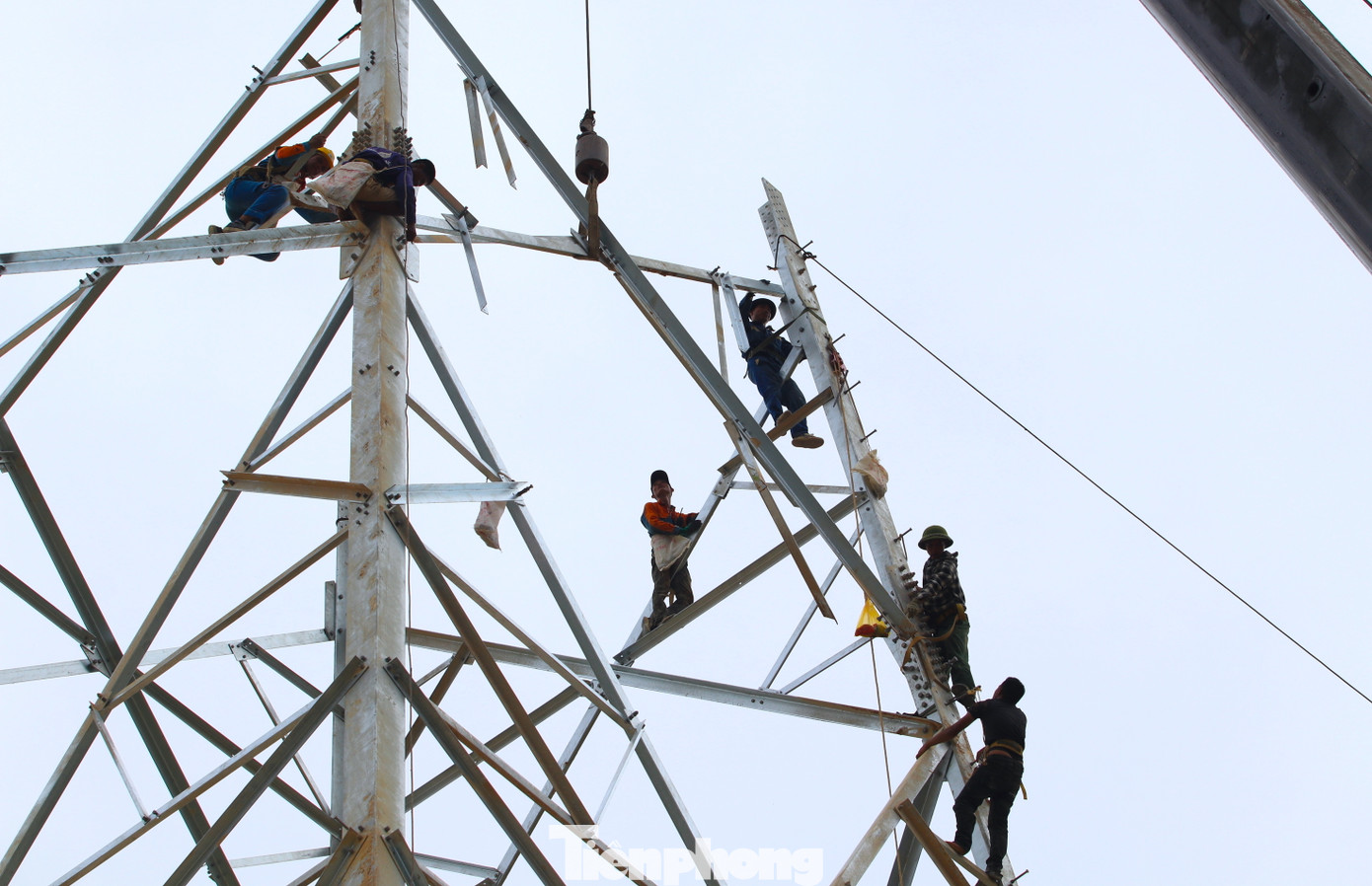 "Cẩu lớn cũng chỉ hỗ trợ cẩu vật liệu và lắp ghép đến cánh xà đầu tiên của cột điện. Còn từ đó lên đến đỉnh phải dùng một chiếc tời rồi kéo lên cao và dùng sức người. Trời mát còn đỡ chứ nắng nóng làm việc vất vả lắm", ông Đặng Đình Toan (54 tuổi) - Đội trưởng đội xây dựng tại cột điện 356 xã Nghi Kiều (Nghi Lộc, Nghệ An) chia sẻ.