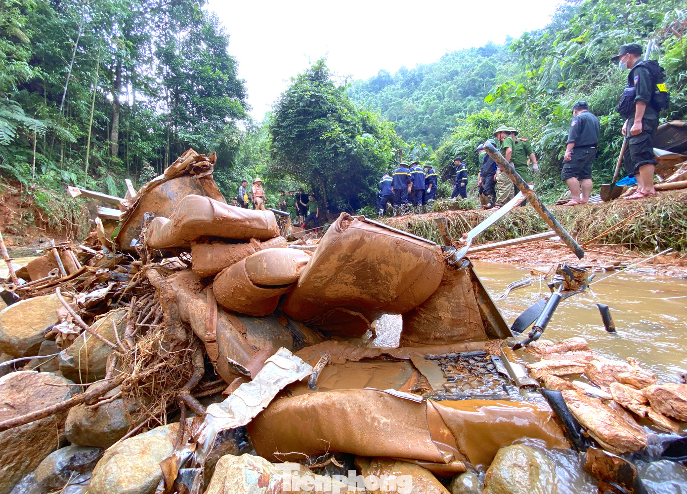 Chiếc xe khách bị vò nát, đất đá vùi lấp xe khiến công việc cứu hộ, trục vớt xe khách ra khỏi dòng suối gặp khó khăn.