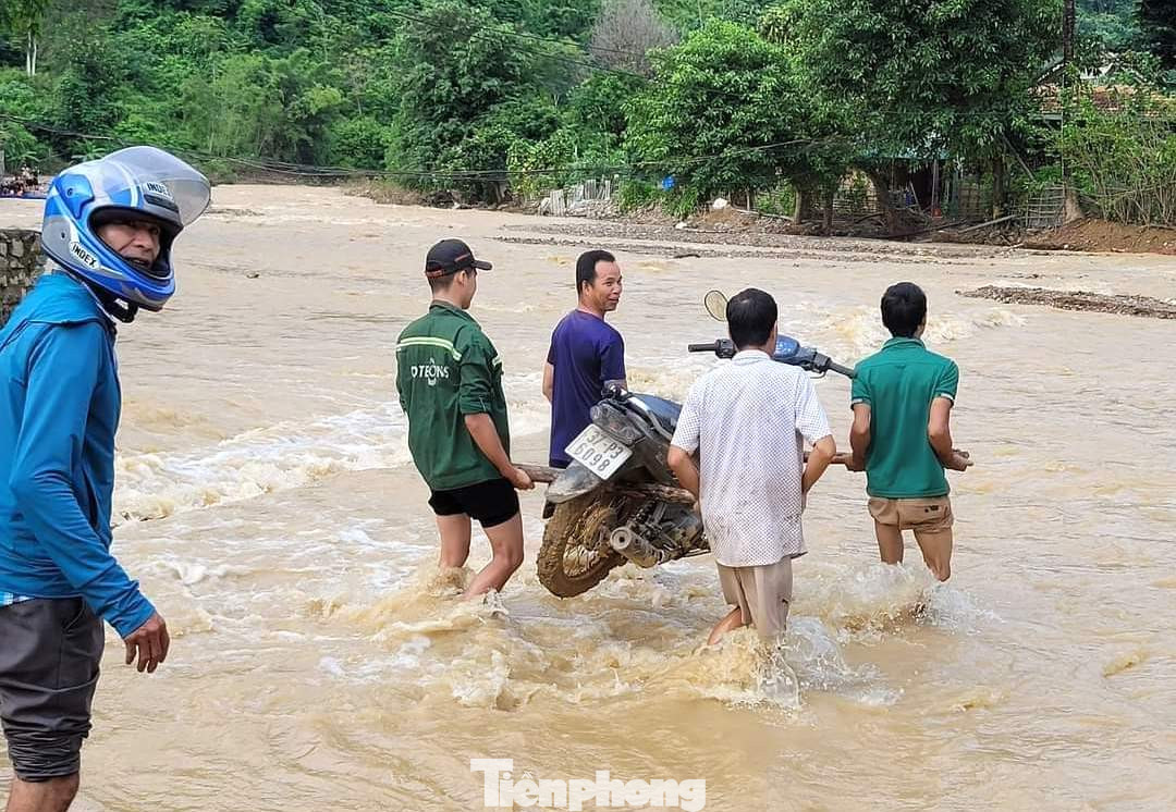 Người dân hỗ trợ khiêng xe máy qua đoạn đường ngập lụt.