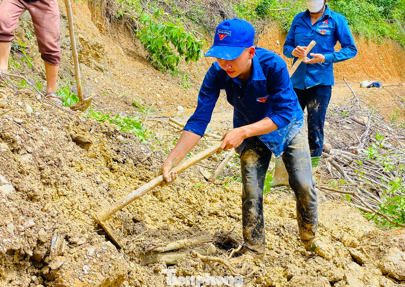 Các đoàn viên lấm lem bùn đất nhưng vẫn miệt mài, cố gắng hết mình để sửa đường bị hỏng sau lũ.