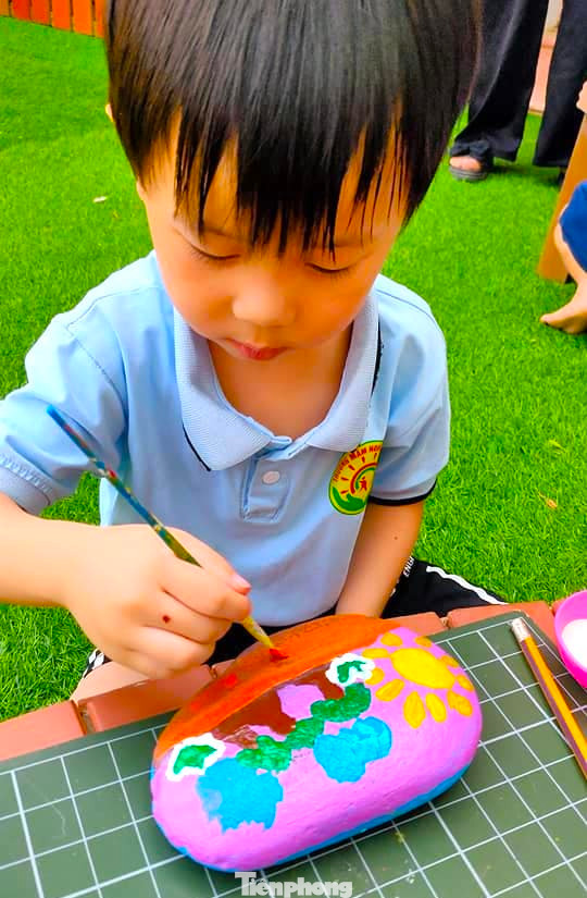 Các em nhỏ thích thú, hào hứng khi được trực tiếp vẽ lên những viên đá tạo tranh.