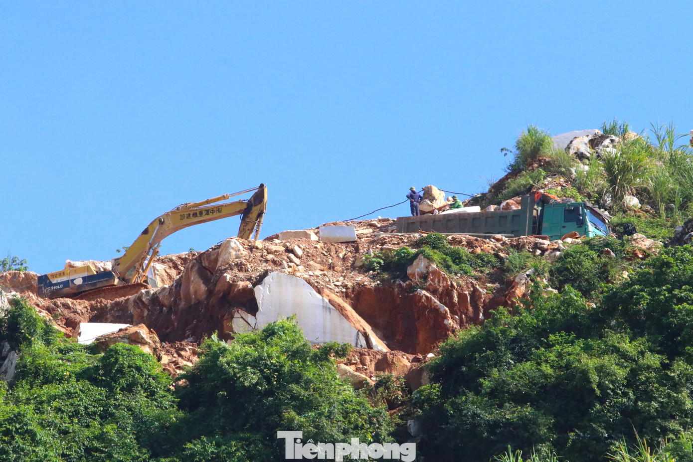 Công nhân cùng máy móc làm việc trên những mỏm núi cheo leo.