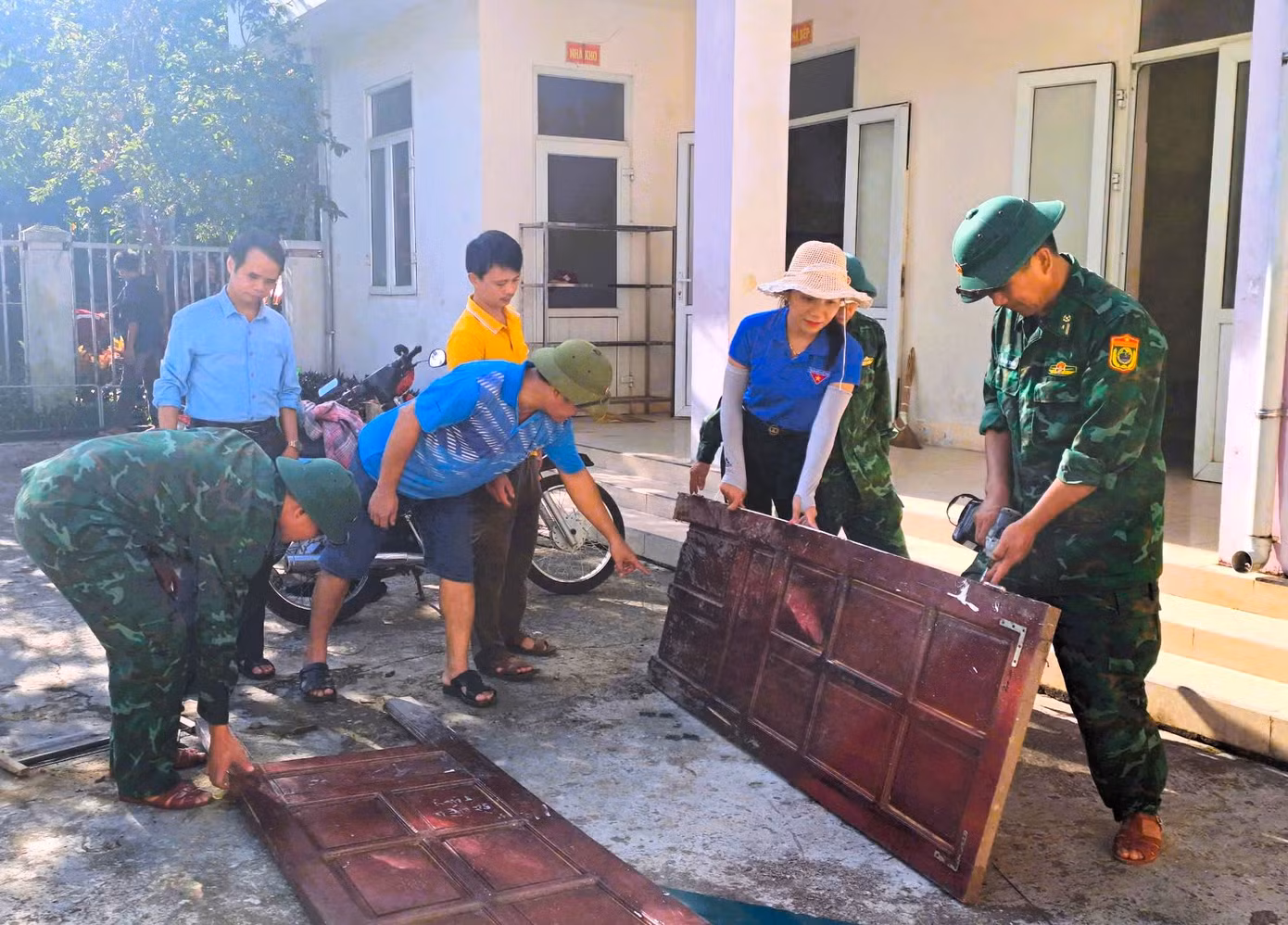 Các cán bộ chiến sĩ biên phòng cùng đoàn viên thanh niên sửa sang lại những cánh cửa đã bị mối mọt hư hỏng.