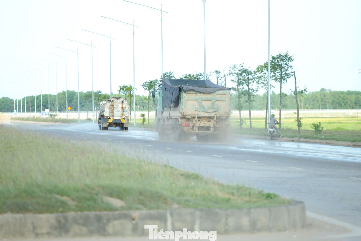 Xe ben vận chuyển vật liệu đi trên tuyến đường N2 khiến bụi bay mù mịt. Dù có xe tưới nước nhưng đất rơi vãi xuống càng khiến tuyến đường trở nên nhớp nhúa.