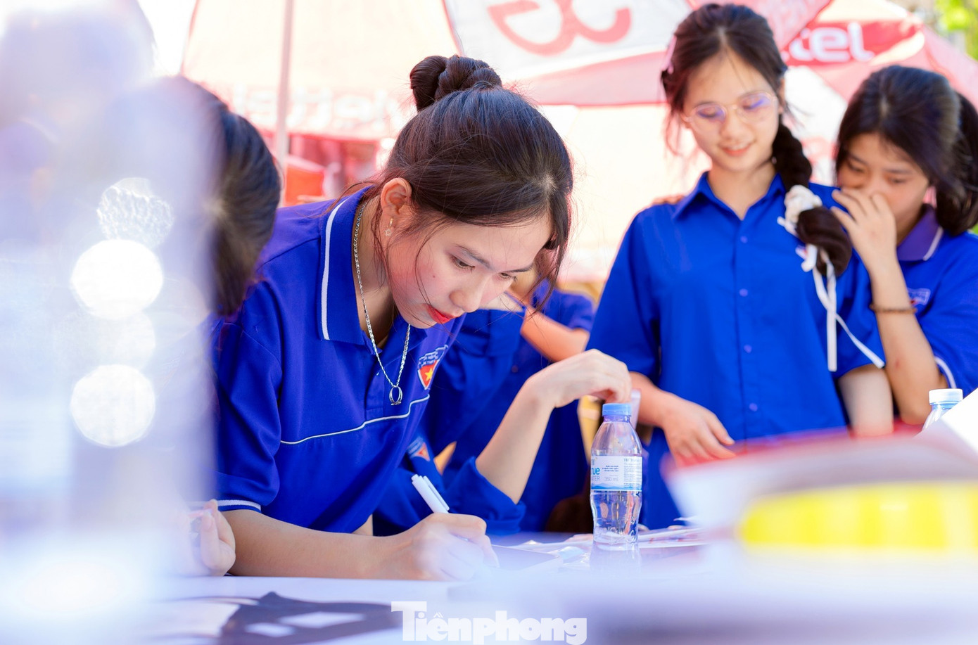 Tại các điểm thi, đội hình thanh niên tình nguyện triển khai nhiều công việc hỗ trợ sĩ tử như: nhận gửi đồ miễn phí, gửi xe, phát nước, phát quạt. (Ảnh: Rạng Đông).