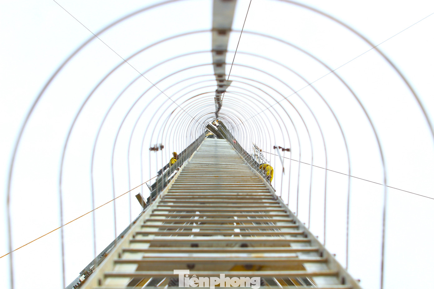 Tại mỗi cột điện sẽ được thiết kế những chiếc cầu thang tạm với vòng tròn bảo vệ bên ngoài để các công nhân leo lên leo xuống làm việc. "Sáng sớm, các công nhân xây lắp leo lên cột điện nhận những thanh cấu kiện rồi lắp ghép thành từng khuông. Trời mát thì có thể làm được cả buổi nhưng nắng nóng thế này chỉ đứng trên được 1 vài giờ đồng hồ rồi phải xuống nghỉ lấy sức", ông Trần Hữu Tuấn (49 tuổi, đội trưởng đội xây lắp Công ty Sông Đà 11) chia sẻ.