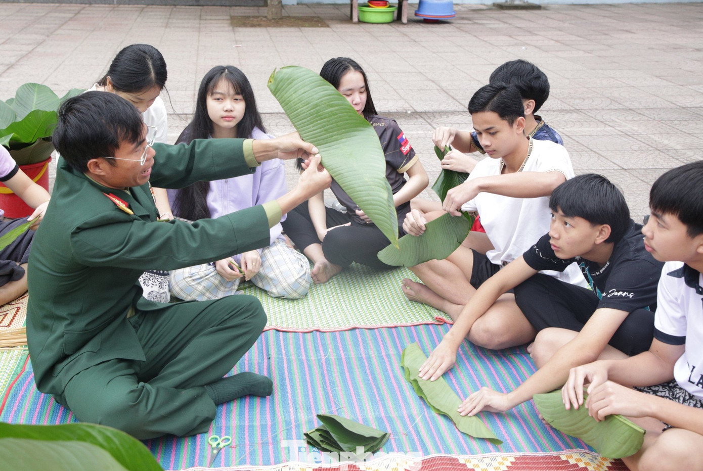 Các cán bộ chiến sĩ hướng dẫn từ việc chọn lá, cắt lá, chuẩn bị nguyên vật liệu đến việc gấp lá và gói bánh.